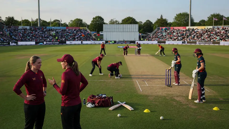 Medium tactical view of fielders set on a sunlit outfield with cones and training markers near the square